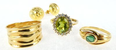 three rings and a ring with a green stone on a white surface