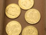 six types différents de pièces d'or dans une boîte posée sur une table
