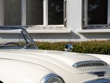 a white vintage car parked in front of a building