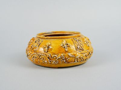 un vase jaune orné d'un motif, posé sur une table
