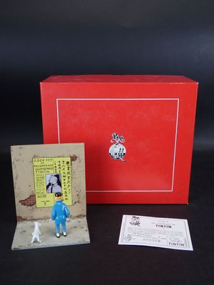 une petite figurine représentant un homme en costume bleu, à côté d'une boîte rouge