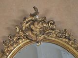 a gold mirror with a bird on top of it
