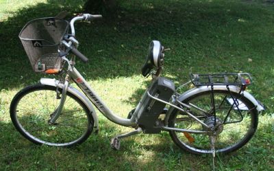 un vélo garé dans l'herbe, avec un panier à l'arrière