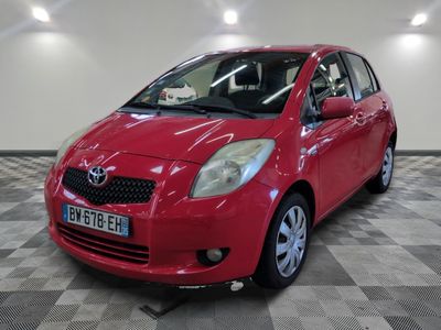 une photo d'une Toyota Yaris rouge garée sur un sol à damier
