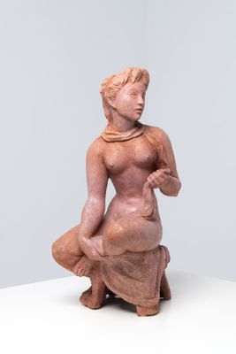 une petite statue représentant une femme assise sur une surface blanche