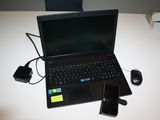 un ordinateur portable posé sur une table, à côté d'un téléphone portable et d'une souris