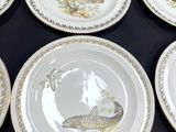 six plates with fish painted on them sit on a black table