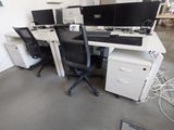 deux ordinateurs posés sur les bureaux de la salle
