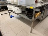 une grande table en métal sur laquelle sont posés de nombreux bols et casseroles