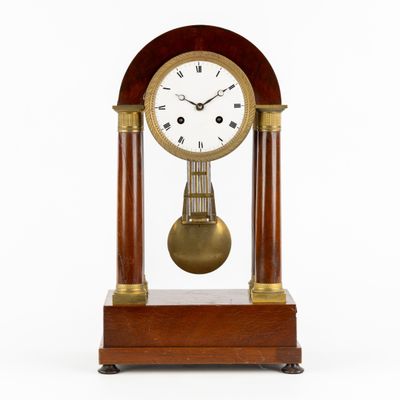 une image représentant une horloge en bois surmontée d'un pendule