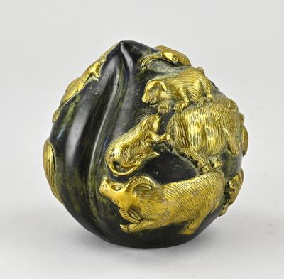 une image représentant une sculpture d'un lion, de couleur or et noire, posée sur un rocher
