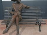 a bronze statue of a woman sitting on a bench