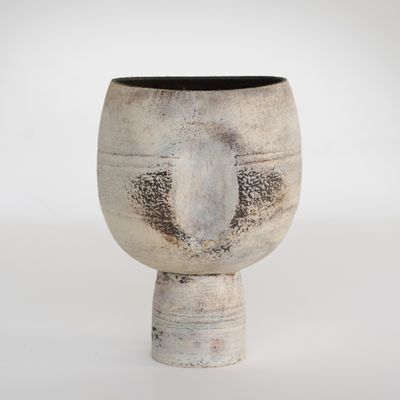 un vase blanc bordé de noir posé sur une surface blanche