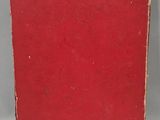 a red book sitting on top of a table next to a white wall