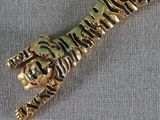 a gold and black tiger brooch on a gray cloth