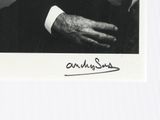 an old photo of a man in a suit and tie with his hand on his chest