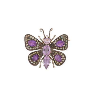 un gros plan d'une broche en forme de papillon ornée de pierres violettes