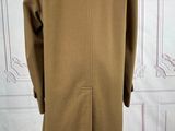 an image of a coat on a mannequin stand in front of a wall