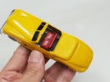 someone is holding a yellow toy car in their hand