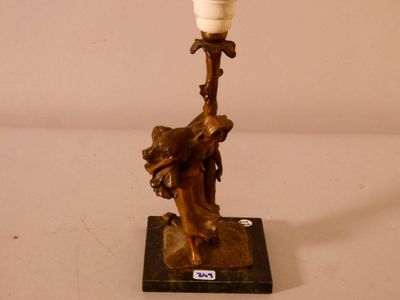 une statue représentant une femme tenant une lampe posée sur une table