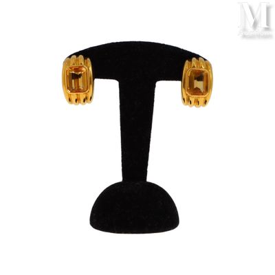 an image of a pair of gold toned earrings on a black stand