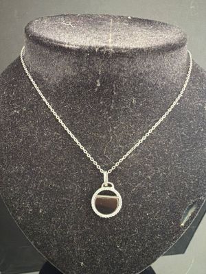 collier plaqué argent avec un pendentif en pierre noire, présenté autour du cou d'un mannequin
