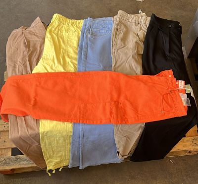 plusieurs paires de pantalons posées sur une palette dans un entrepôt