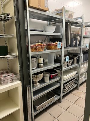 many shelves in the kitchen with pots and pans on them