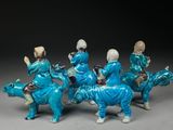 four figurines of people riding horses with a dog