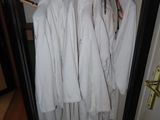 many white robes hanging on a rack in a closet