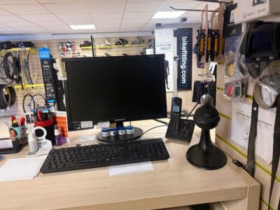 a desk with a monitor, keyboard, mouse and other items on it