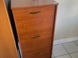 une commode en bois à trois tiroirs placée près d'une fenêtre