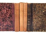 plusieurs vieux livres sont alignés sur une surface blanche