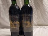 two bottles of wine sitting on top of a white sheet