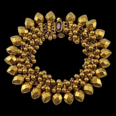 a close up of a gold bracelet on a black background
