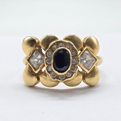 a close up of a gold ring with a blue stone surrounded by diamonds