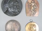 Quatre médailles de tailles et de formes variées sont exposées sur une table