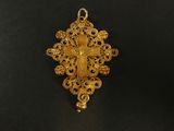 un pendentif en forme de croix en or, orné de motifs en filigrane sur fond noir