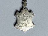 a close up of a small silver pendant on a white surface
