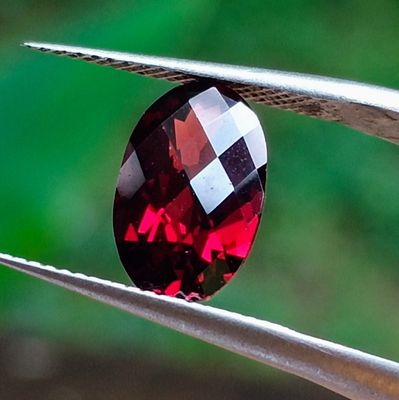 un gros plan d'une pierre rouge tenue par une pince