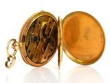 a gold pocket watch with a chain on a white surface