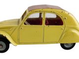 une petite voiture jaune posée sur une surface blanche, à côté d'un mur blanc