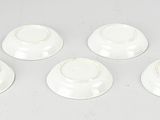 four white cups and saucers sitting on top of a white table