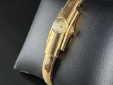 a close up of a watch on a pillow on a black surface