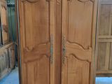 a wooden armoire in a room with many wooden cabinets
