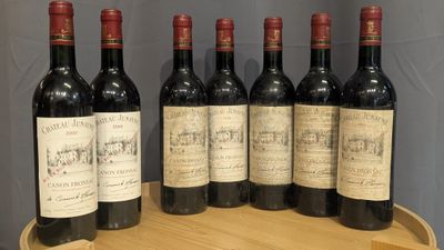 six bottles of red wine are lined up on a wooden barrel