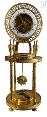 une horloge dorée posée sur un socle, sur fond blanc