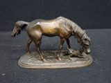 a bronze statue of a horse and a dog on a table