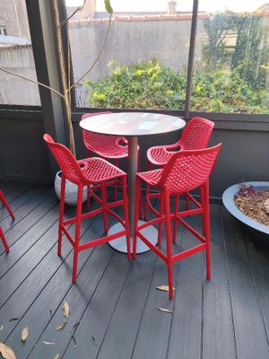 quatre chaises rouges et une table sur la terrasse