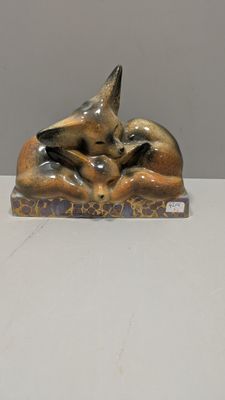 une figurine représentant un chat allongé sur un livre